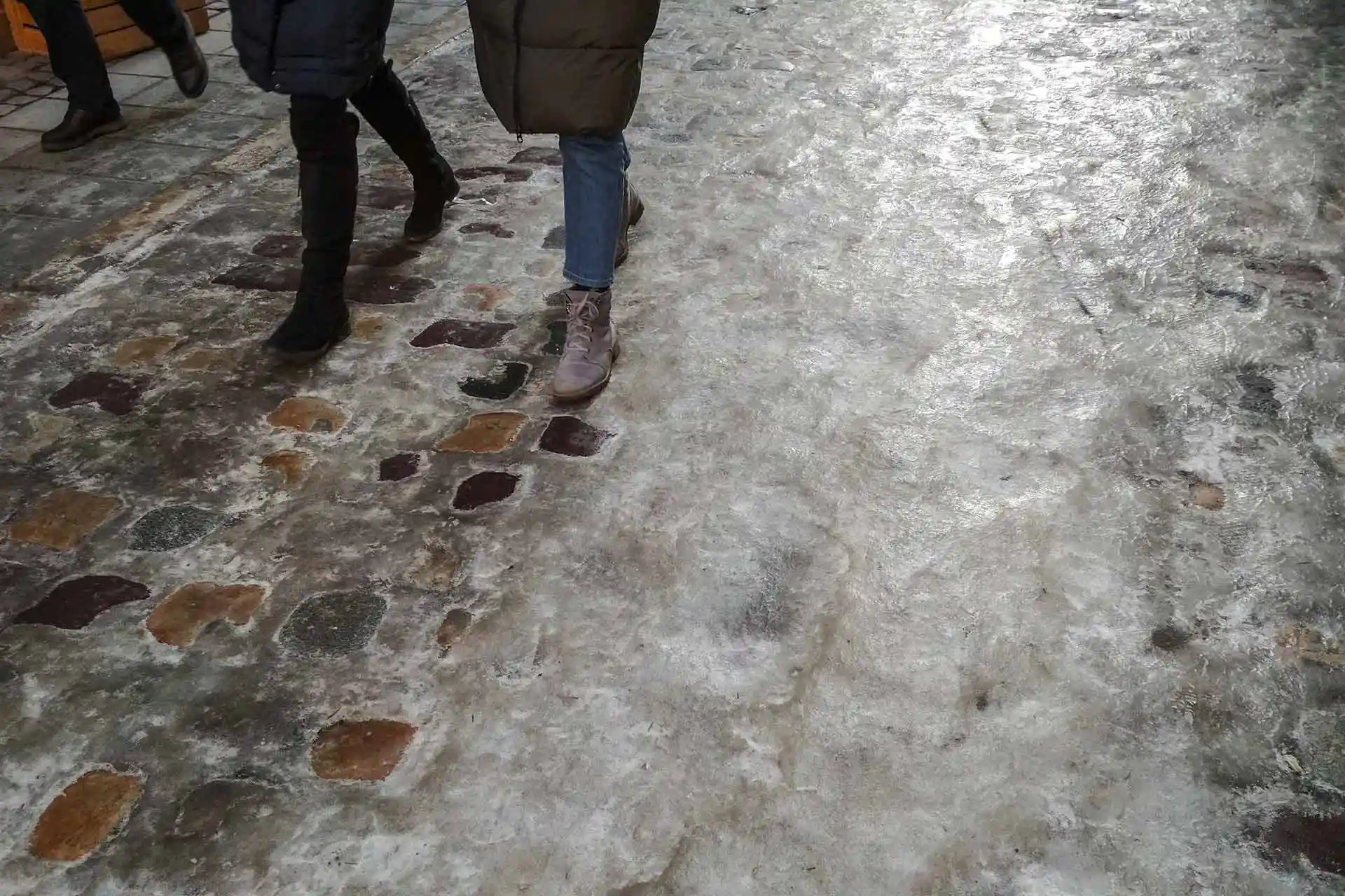 Several people walk on a stone street with coats on