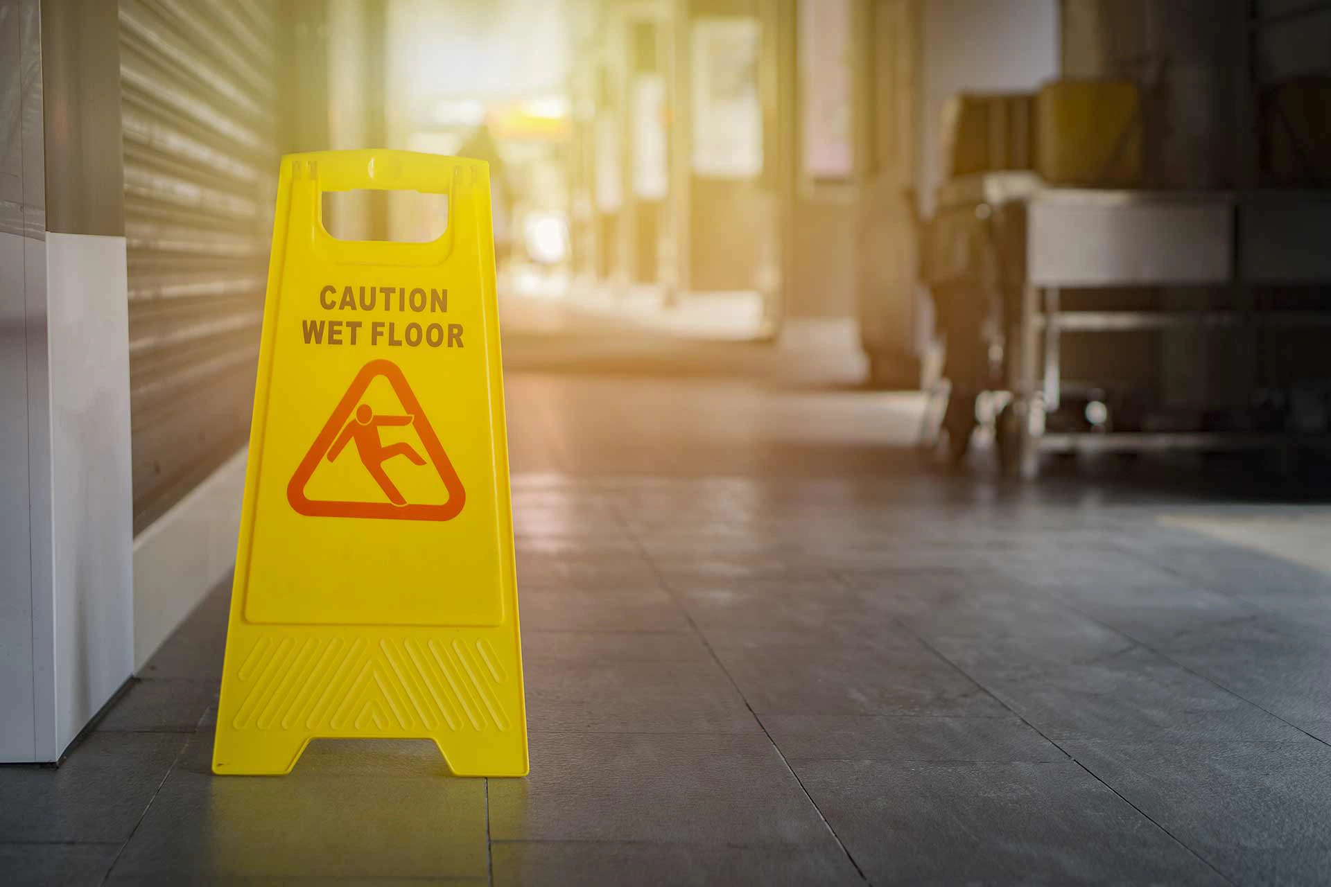 A yellow wet floor caution sign is on a stone floor in a business
