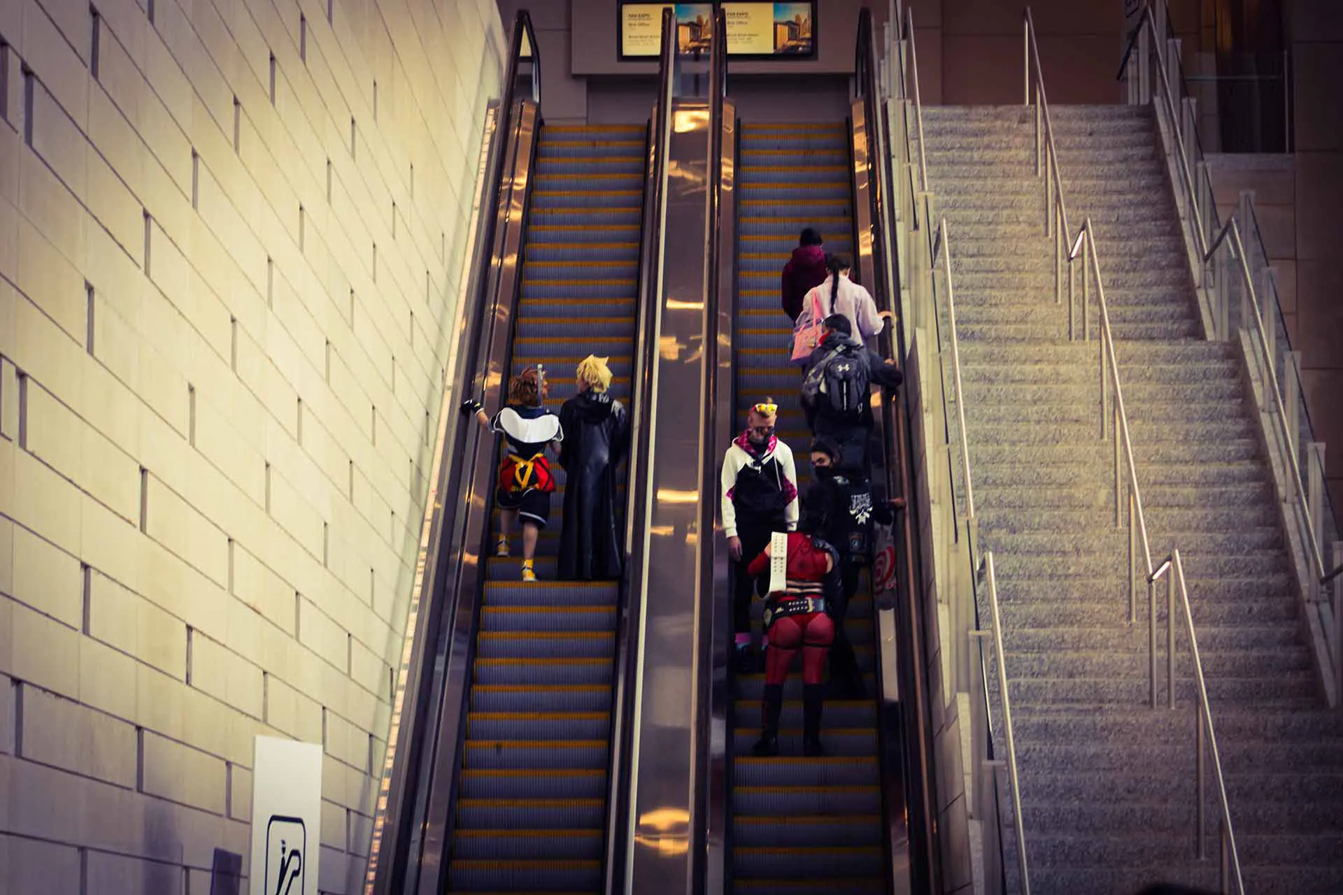 A group of people dressed up in costumes ride up a city escalator